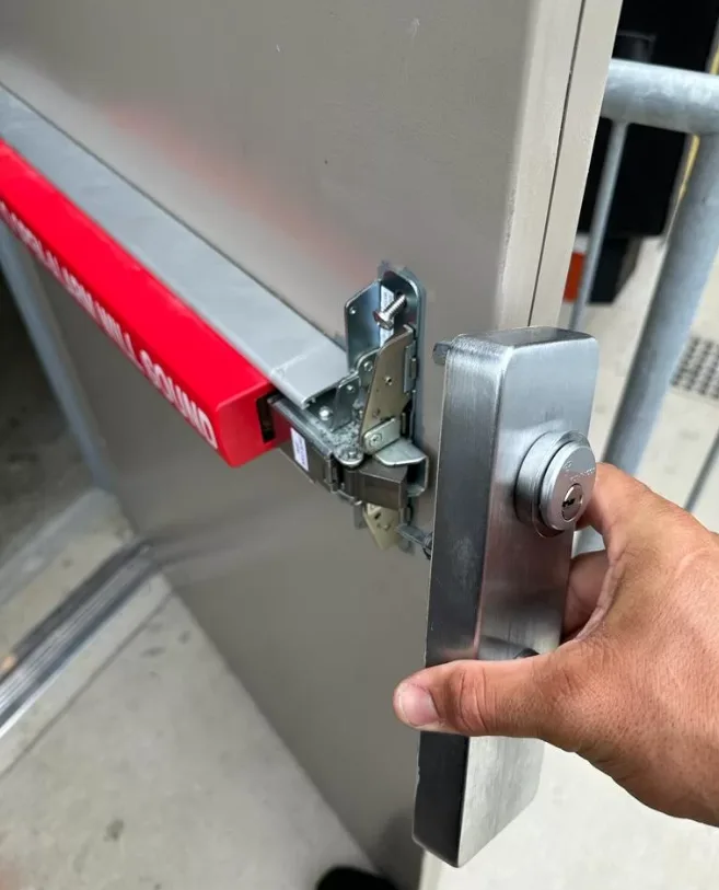 Triton Locksmith installing alarmed exit device on commercial emergency door in South Florida